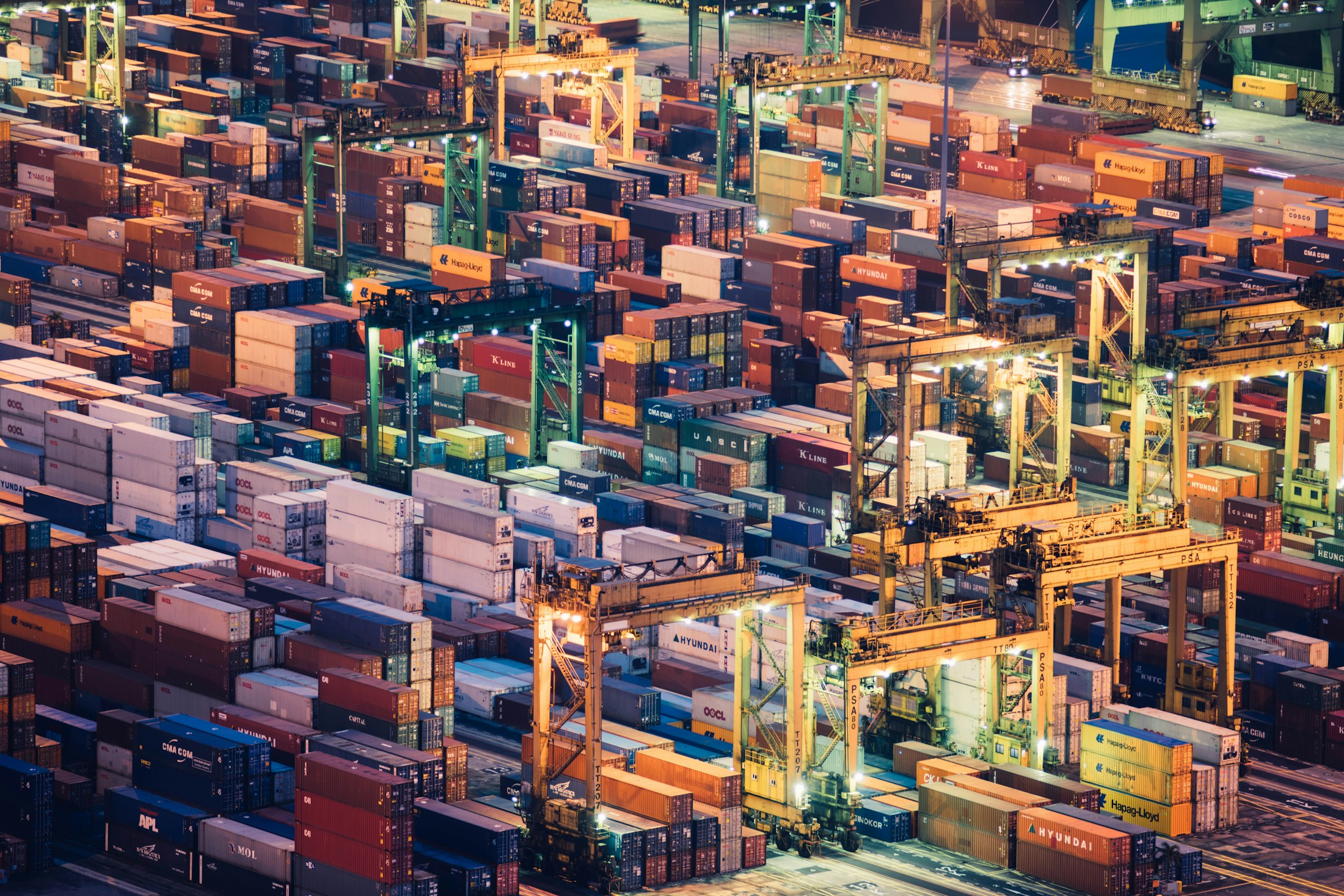 Rows of shipping containers and transport lanes at a port at night